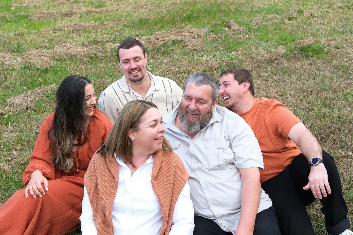 A group lounging together on grass sharing laughs and smiles.