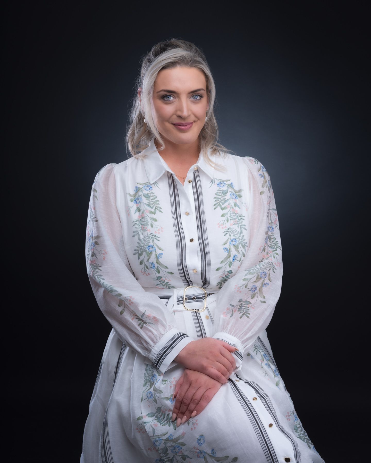 A figure in a white embroidered dress with floral details poses against a dark background in a series of elegant shots.