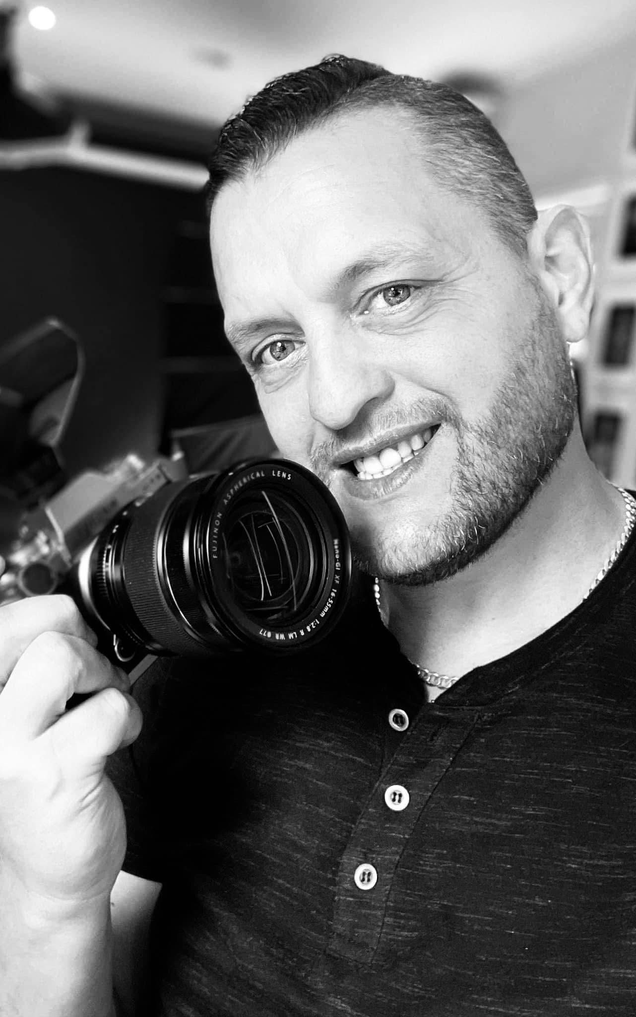 Black and white portrait of photographer holding camera with professional lens.