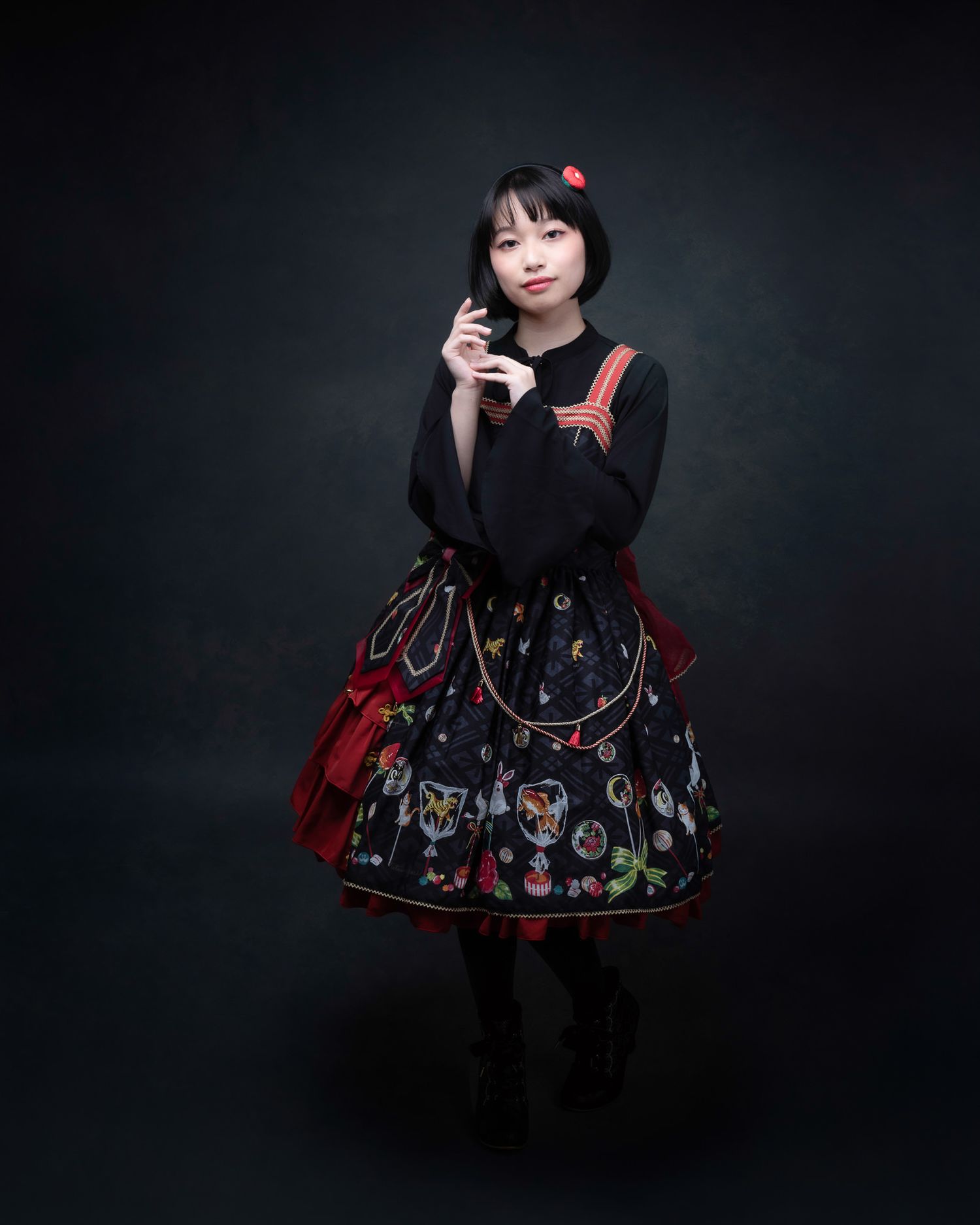 Dramatic portrait of a figure in gothic lolita fashion with a patterned skirt and black top against a dark background.