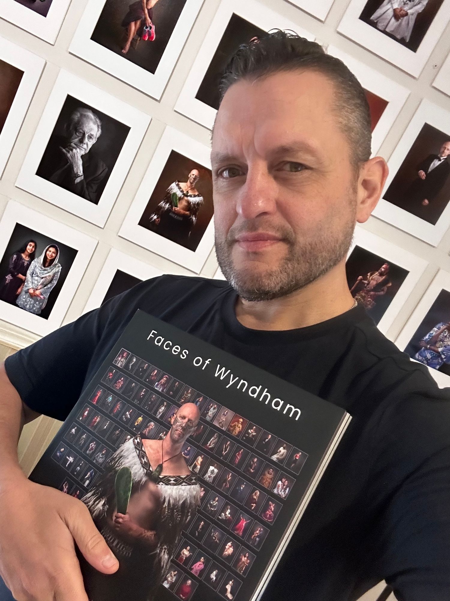 Someone displays a dark photo album or portfolio containing multiple small photographs arranged in a grid pattern.