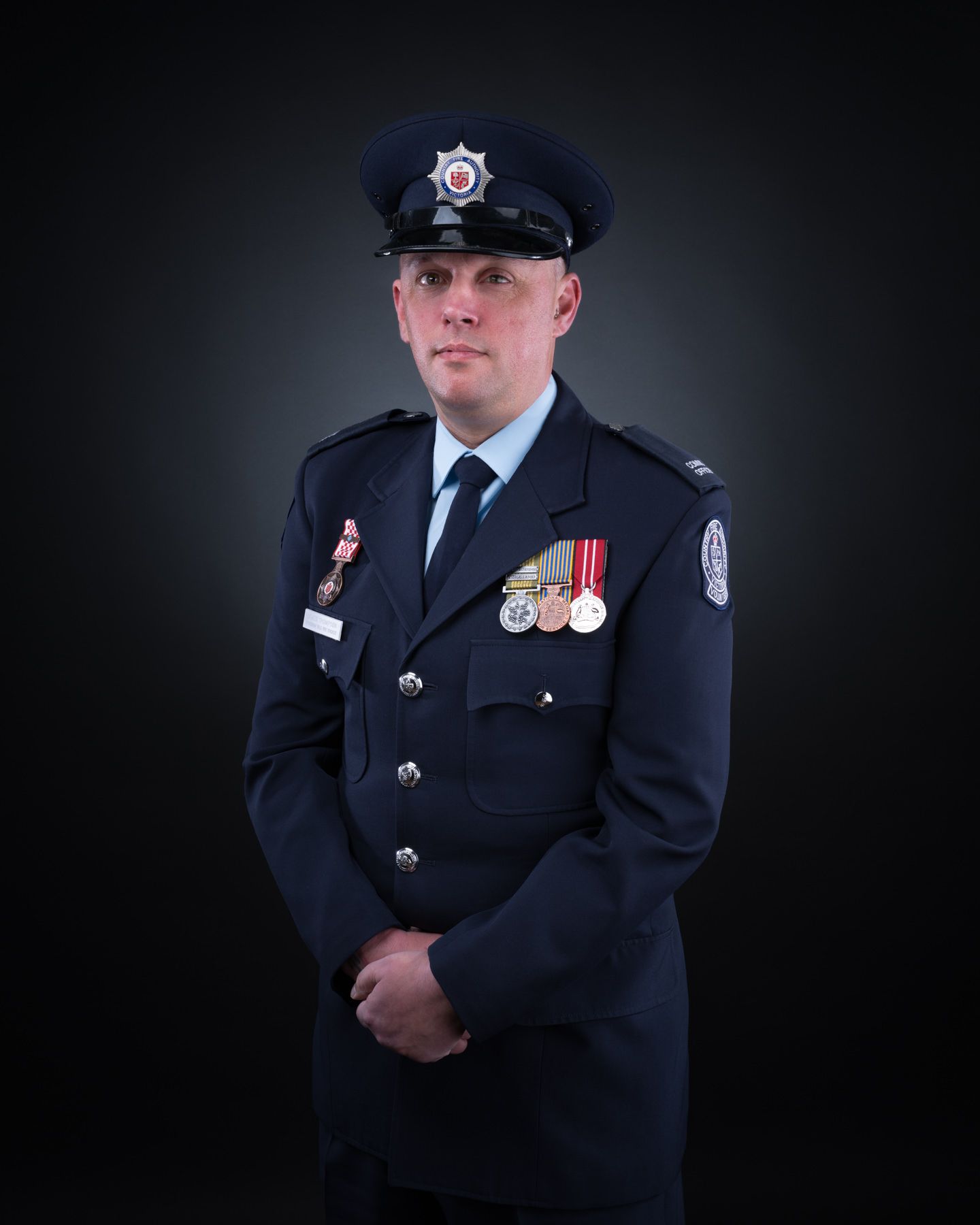 Military or police service members in dress uniforms photographed against a dark backdrop.