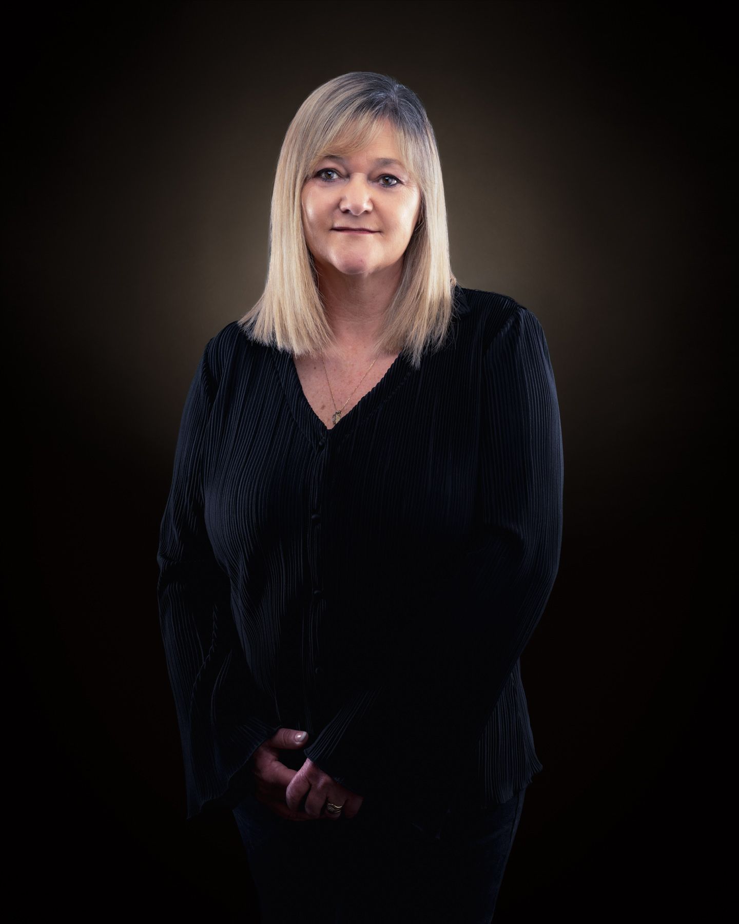 Professional studio portraits on dark background show person in black clothing against dramatic lighting.