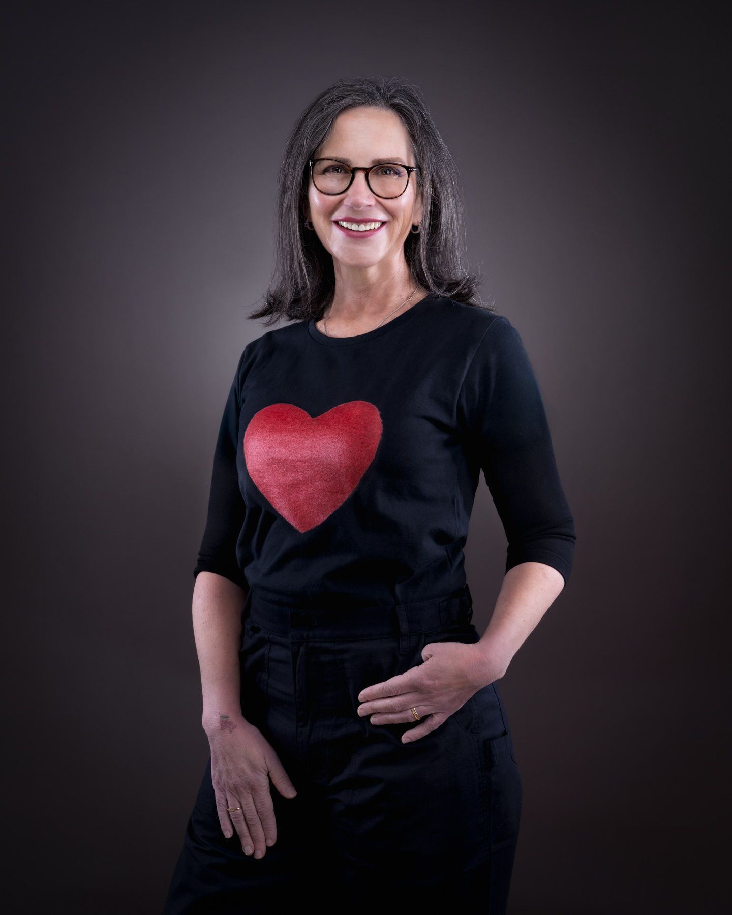 A series of portraits showing someone in a black shirt with a red heart design against a dark background.