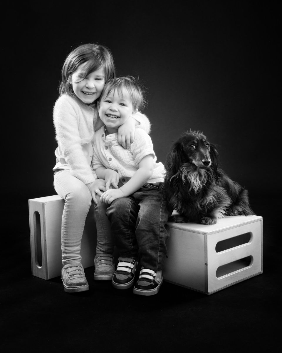 Black and white photo series showing a child and puppy bonding on a white bench in various playful poses.