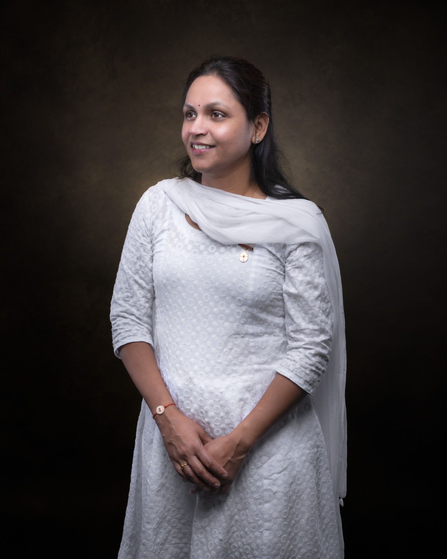 A person in a white lace dress poses against a dark background in a series of elegant portrait shots.