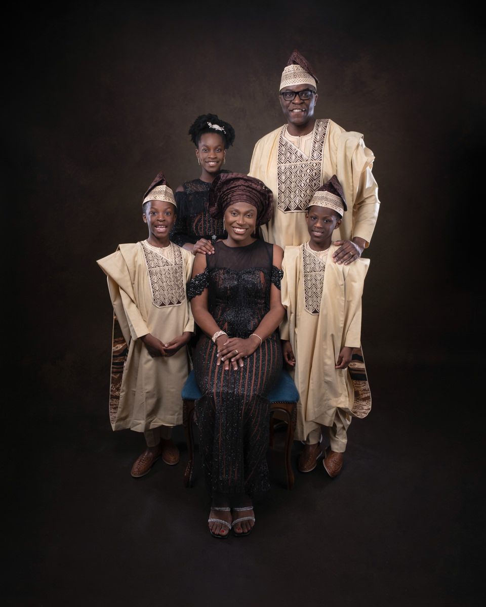 A family wearing traditional African attire poses together against a dark studio background in a series of portraits.