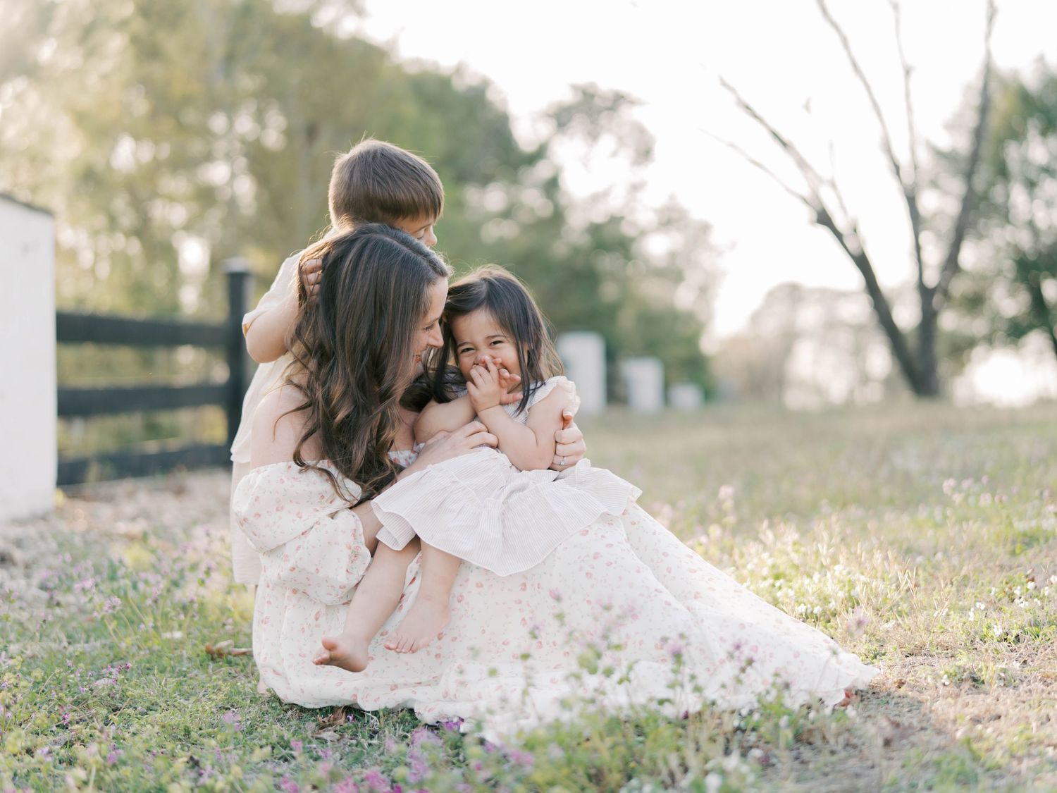 Family sharing tender moment together sitting in field of wildflowers at sunset.