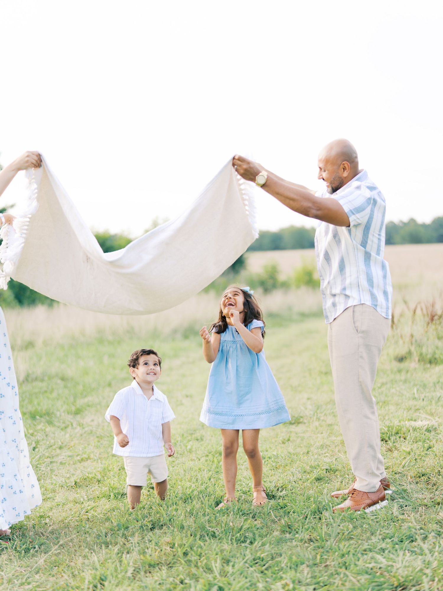 A group of people in white and blue outfits dance together in a grassy field on a bright sunny day.