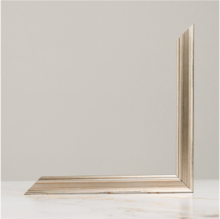 Elegant silver picture frame corner detail displayed on marble surface against neutral gray background.