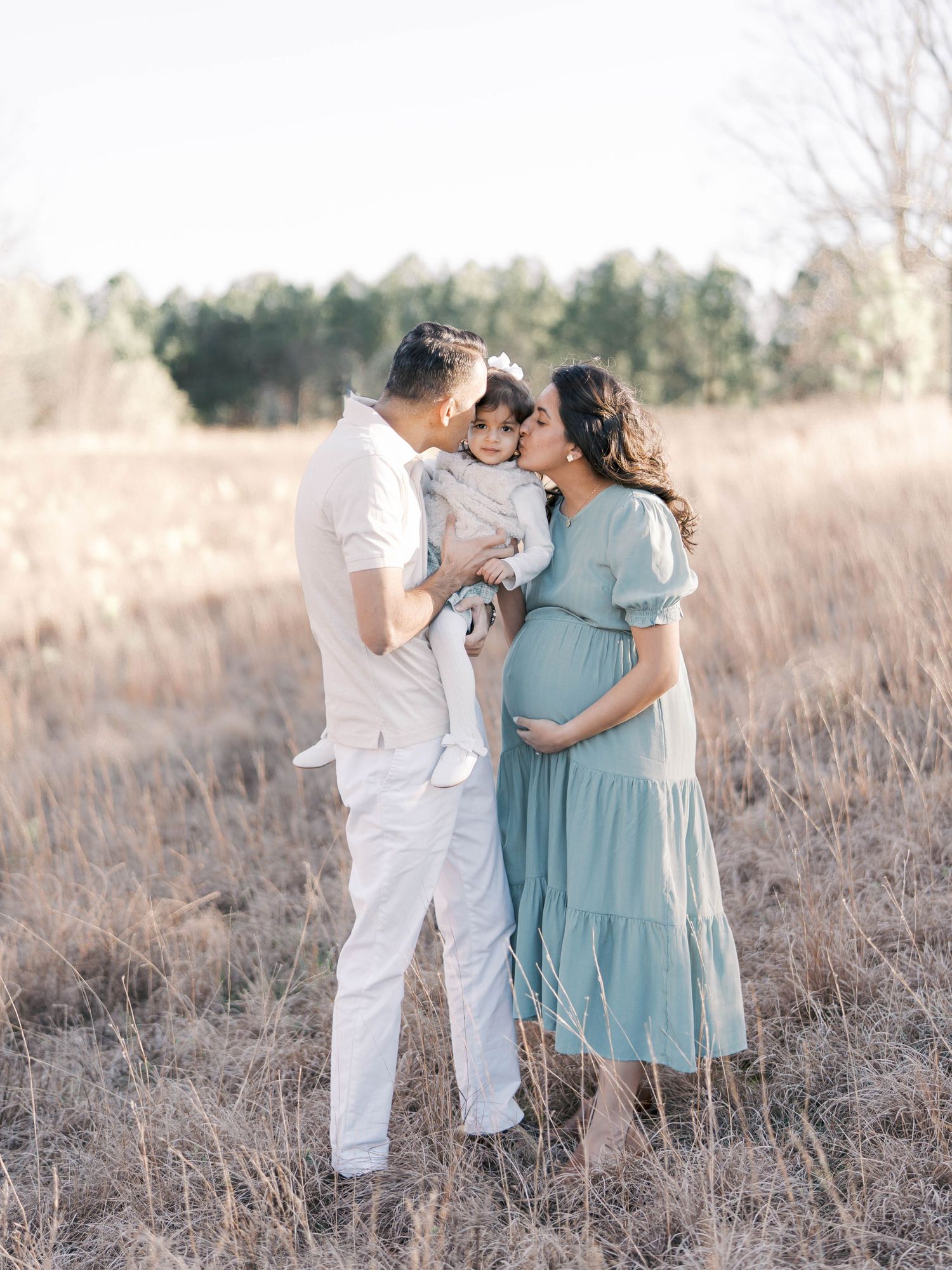 Intimate maternity portrait in a serene field during sunset.