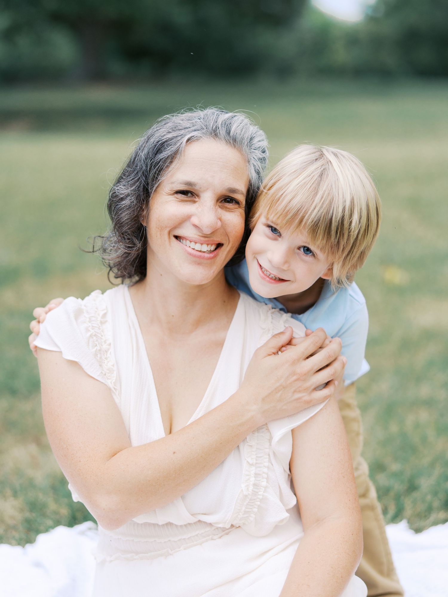 A heartwarming series of candid moments between a parent and child embracing outdoors in matching white outfits.