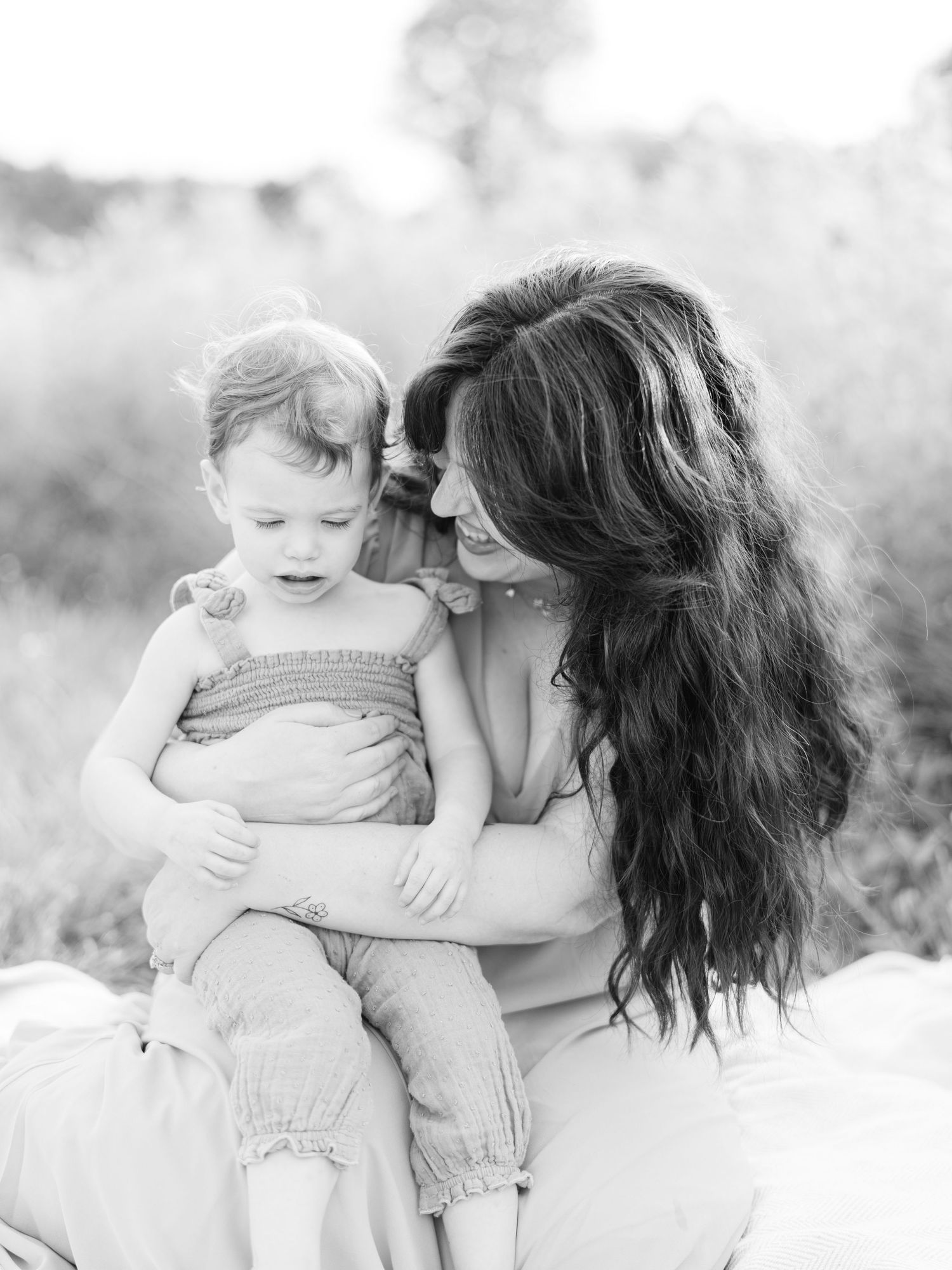 A tender black and white portrait series showing a mother and child sharing joyful moments together outdoors.