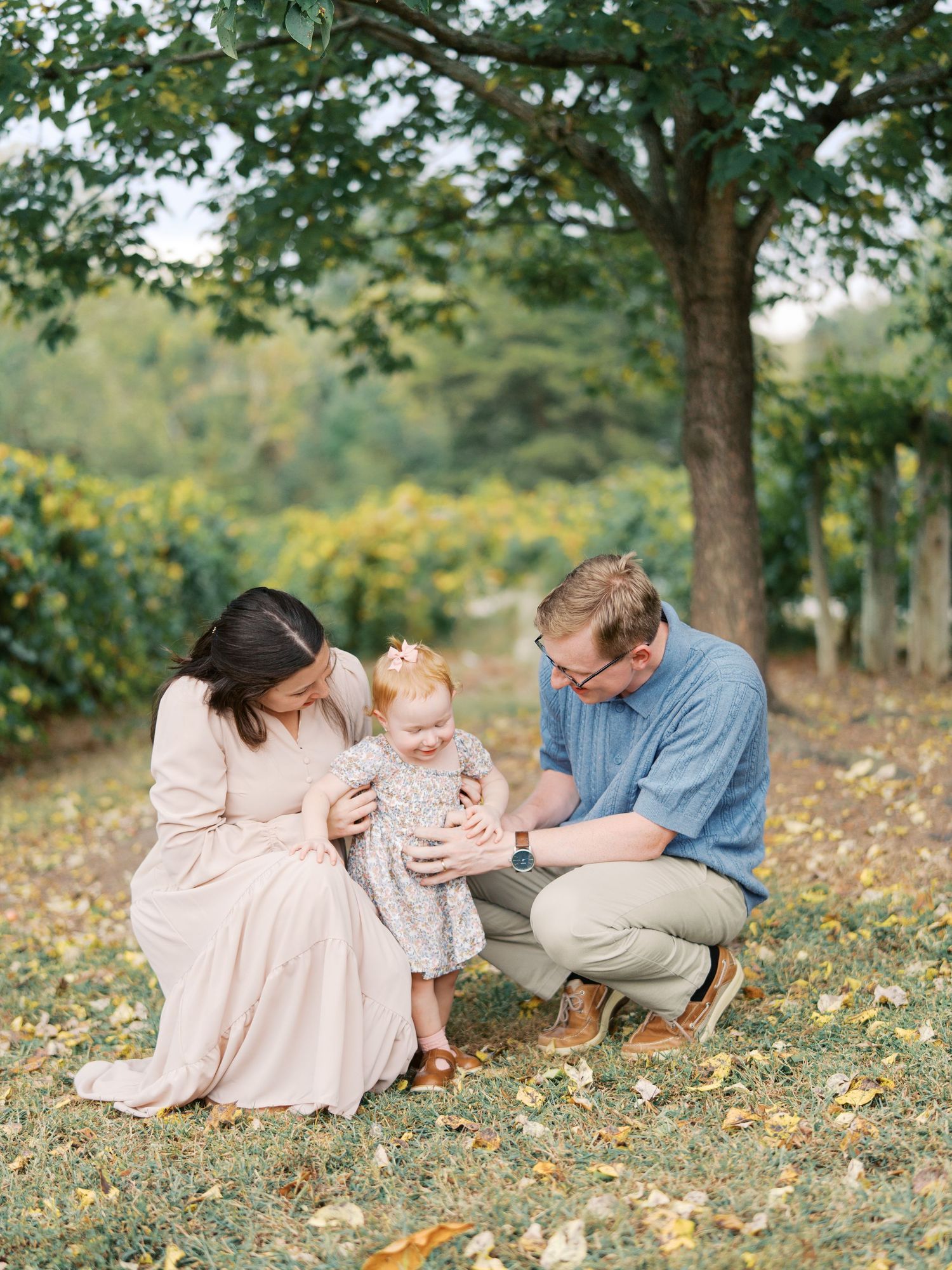 A family sits together on autumn grass surrounded by yellow wildflowers in a serene outdoor setting.