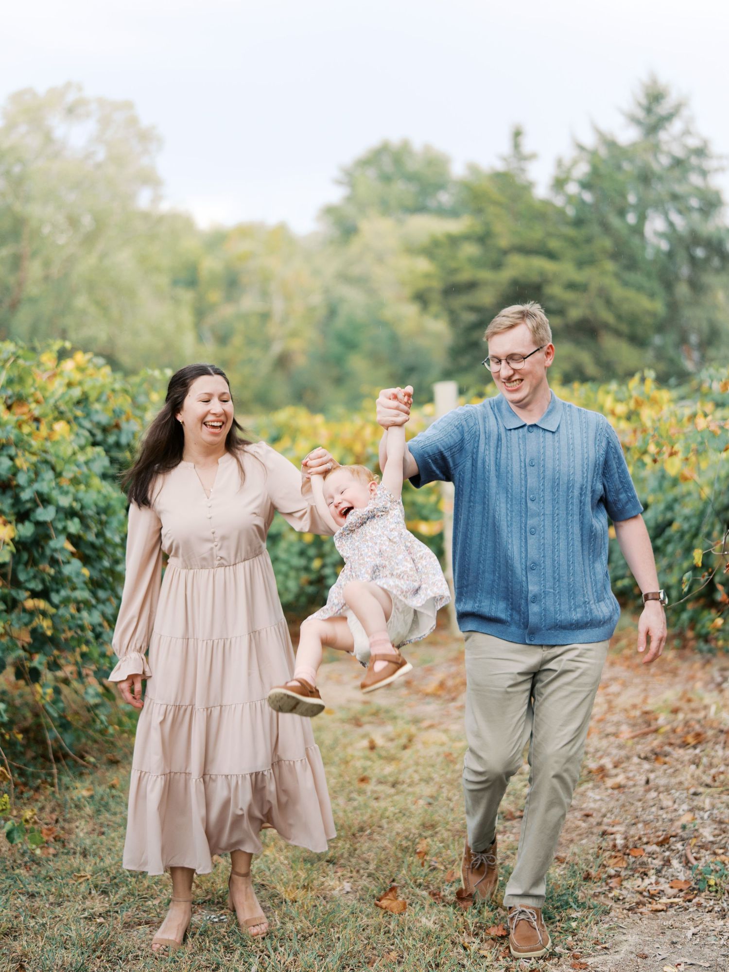 A joyful family photo session in a garden with people wearing coordinated outfits in blue and beige tones.