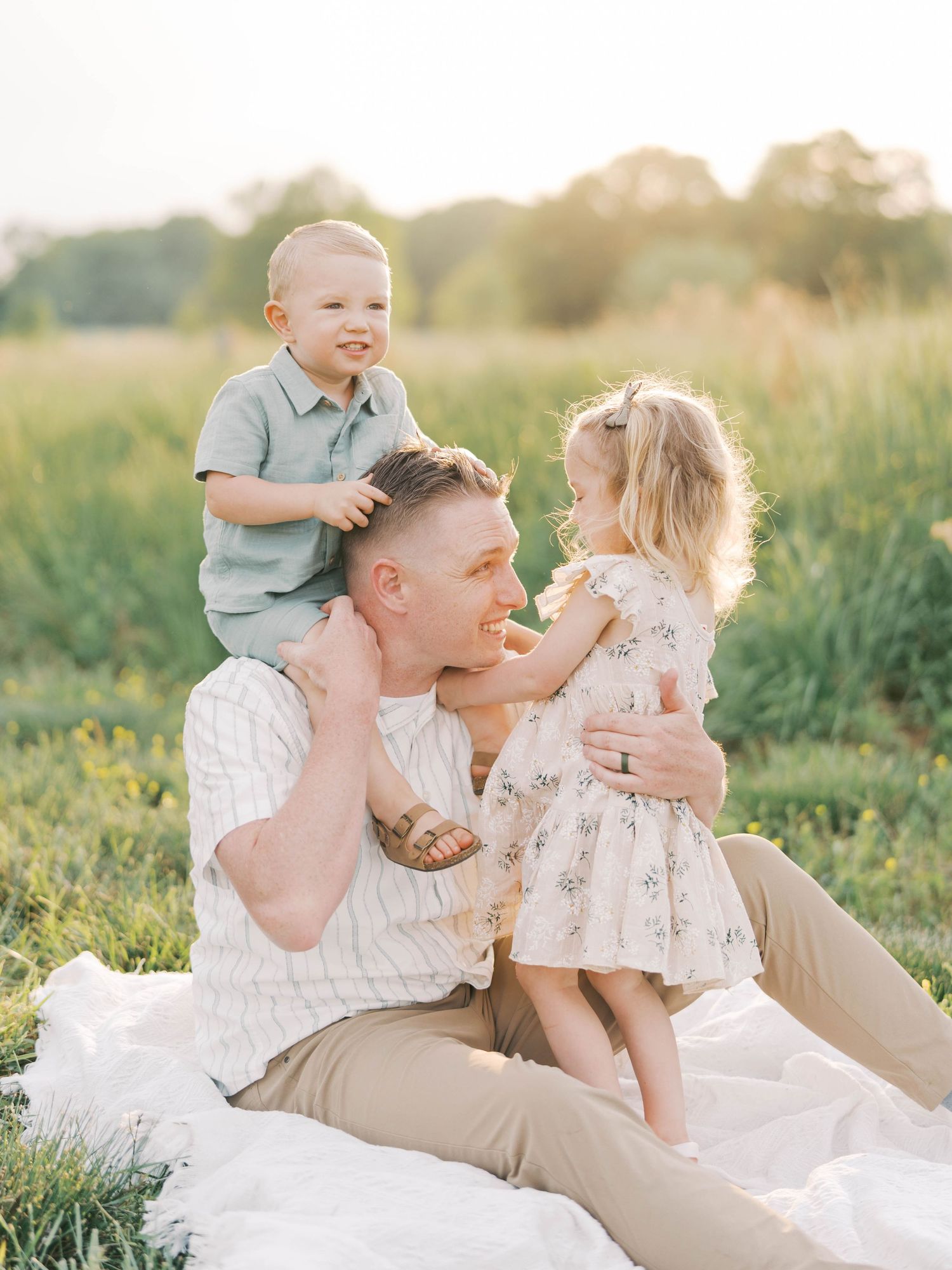 Joyful family sharing intimate moments while relaxing on picnic blanket in sunlit meadow.