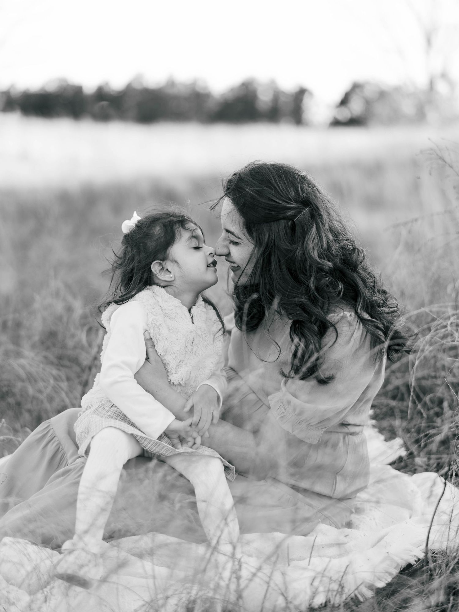Black and white portrait capturing a tender moment in tall grass.