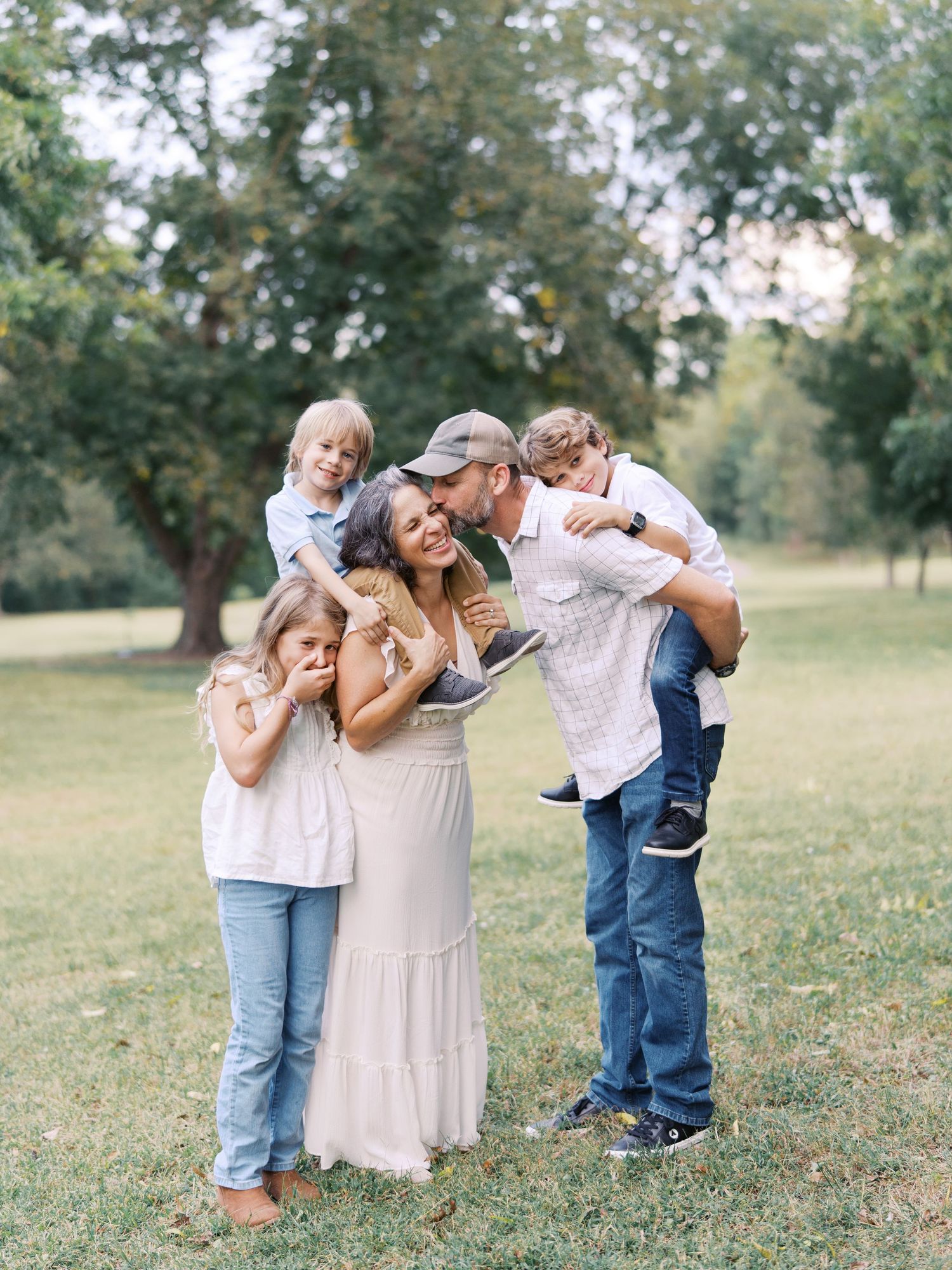 Family sharing joyful moments together in a sunny field with trees in the background.