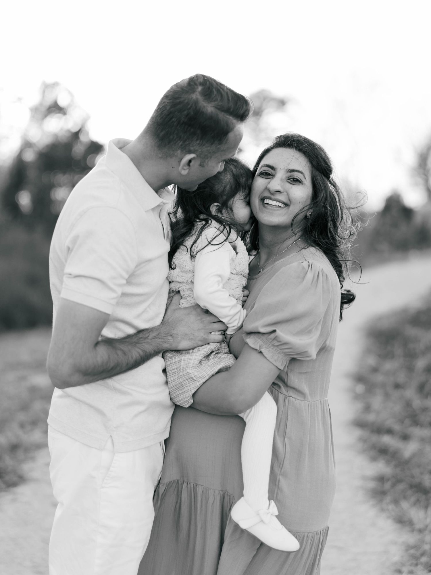 Black and white portrait of family sharing intimate moment together outdoors.