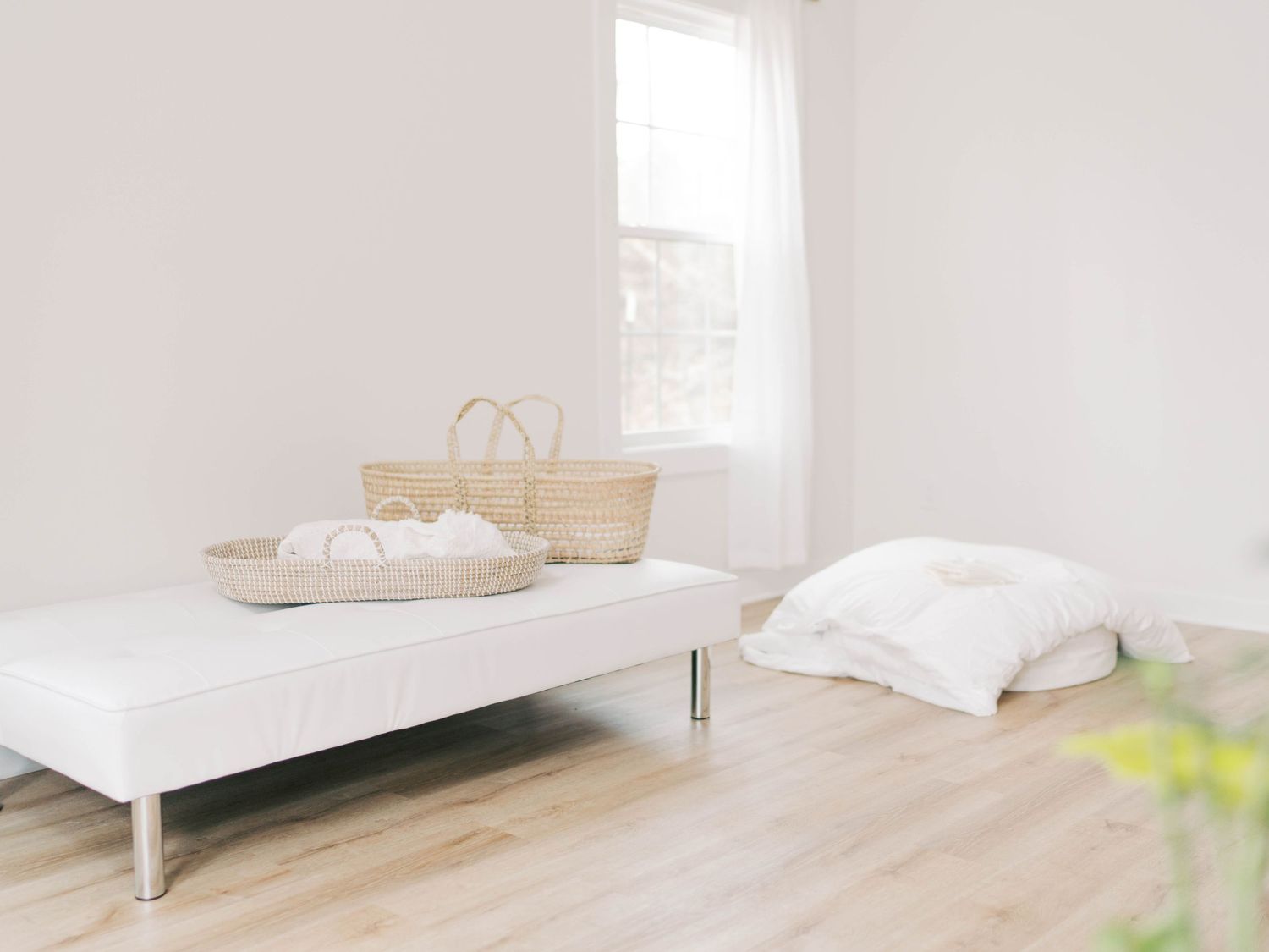 Modern white daybed with natural woven baskets in a sunlit room.