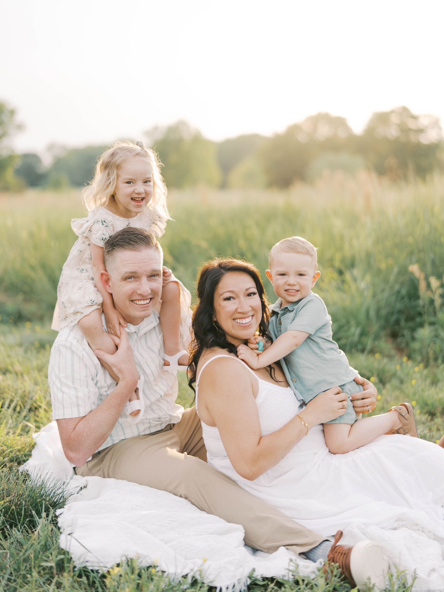 Joyful family photo session in nature with children on shoulders.