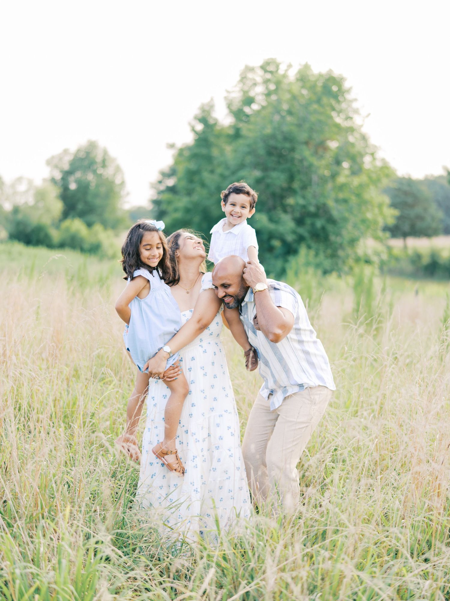 A couple shares tender moments in a sunlit meadow with tall grass during a romantic outdoor photo session.