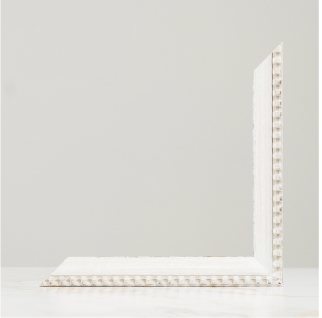 White L-shaped corner molding trim piece with decorative beaded edge detail, shown against a neutral gray background.