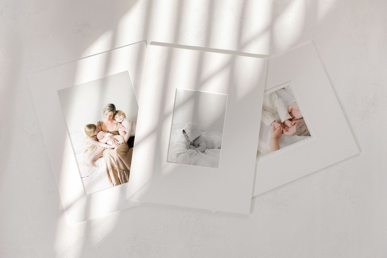 Three elegant portrait photos arranged on a white surface with soft natural light and shadows creating a serene display.