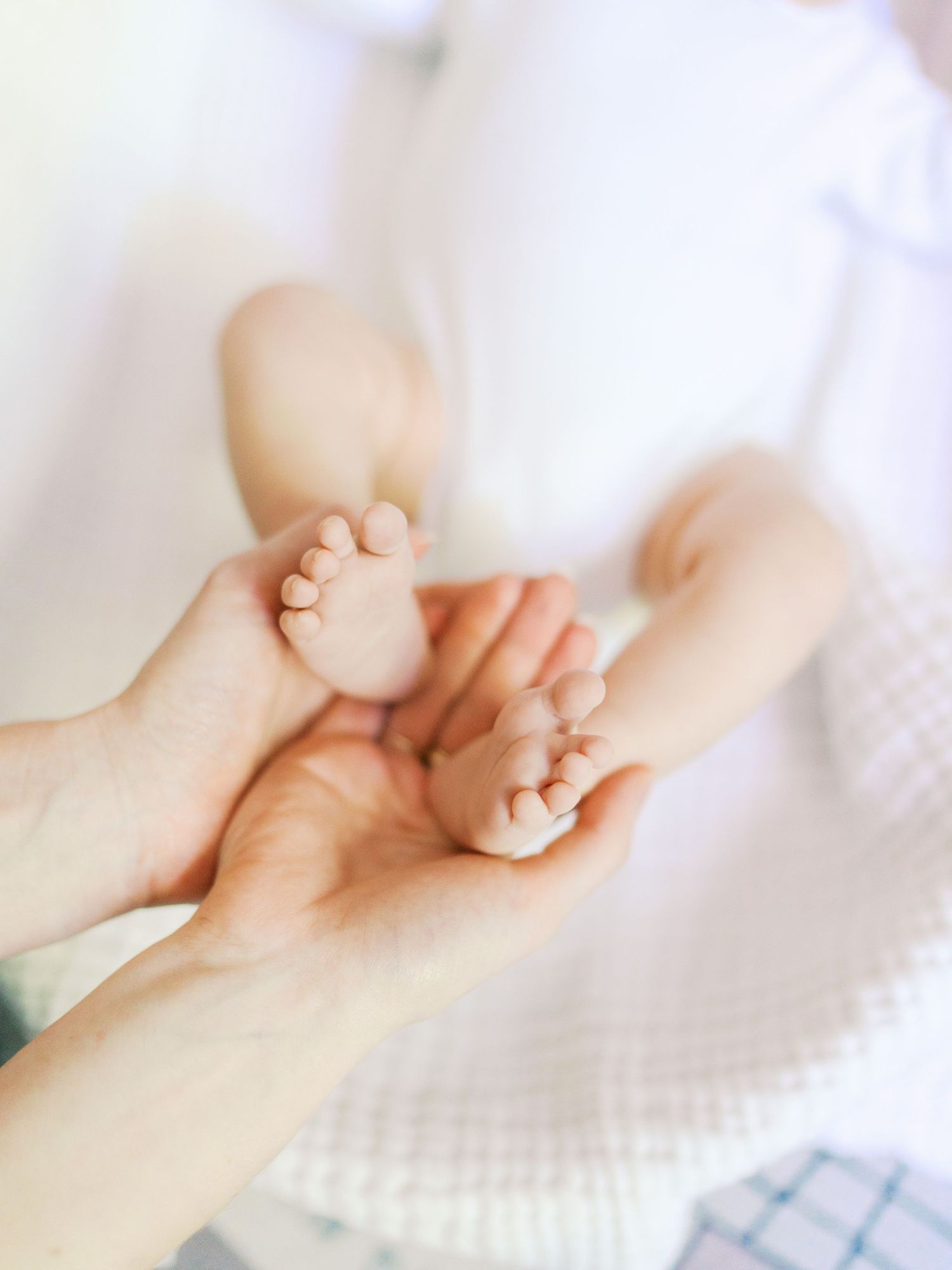 Adult hands gently cradling tiny newborn baby feet, showcasing the delicate bond between parent and child.