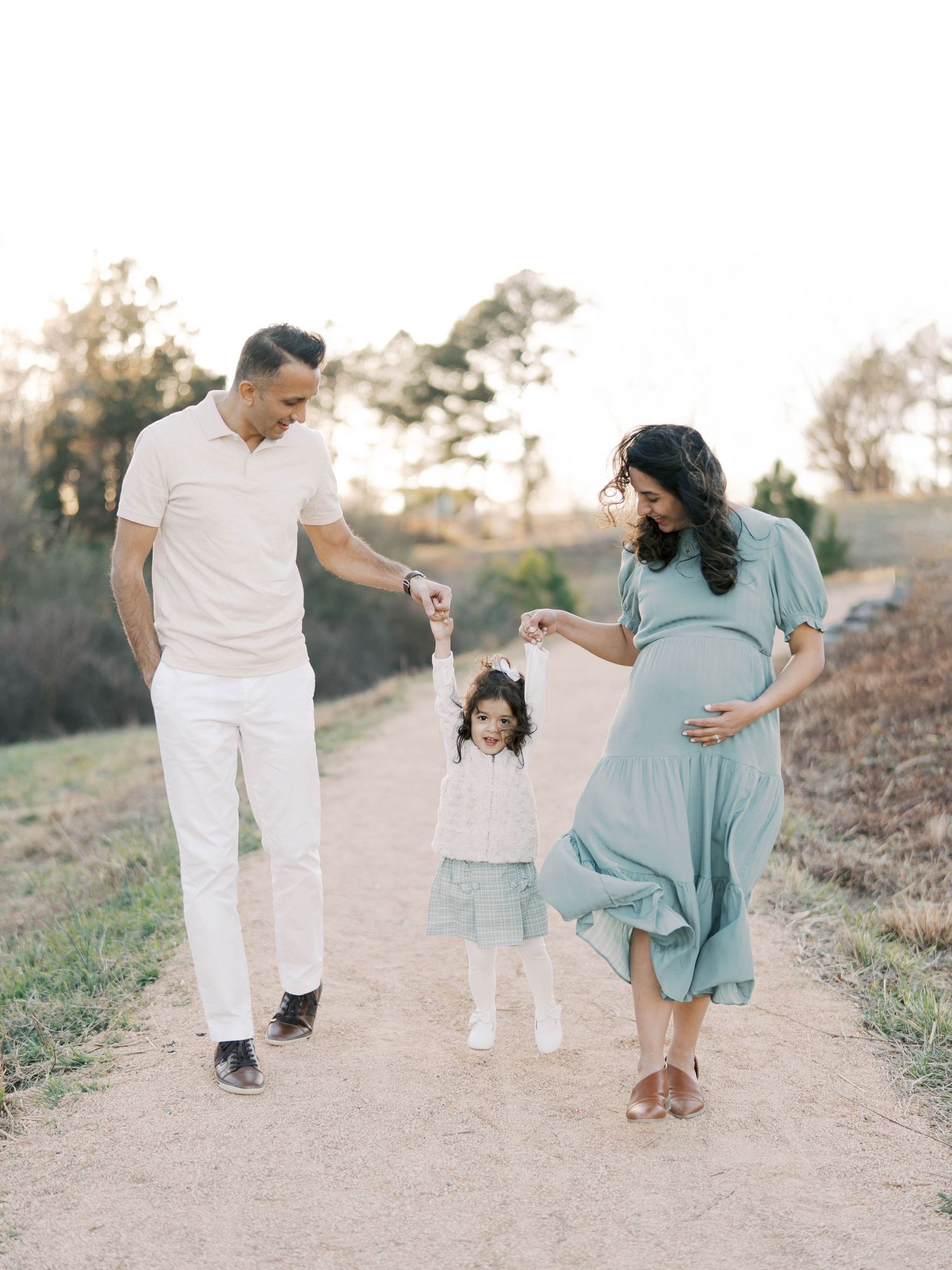 Family walking together on a dirt path during golden hour.