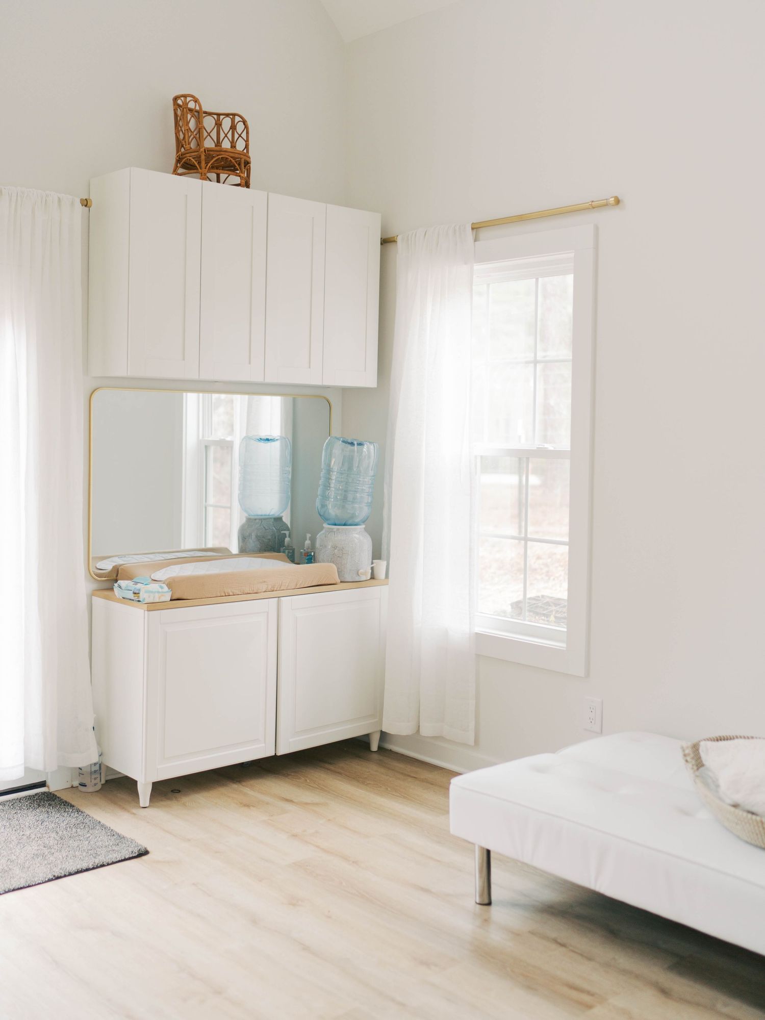 Bright minimalist bedroom with white storage cabinet, mirror, and modern daybed.
