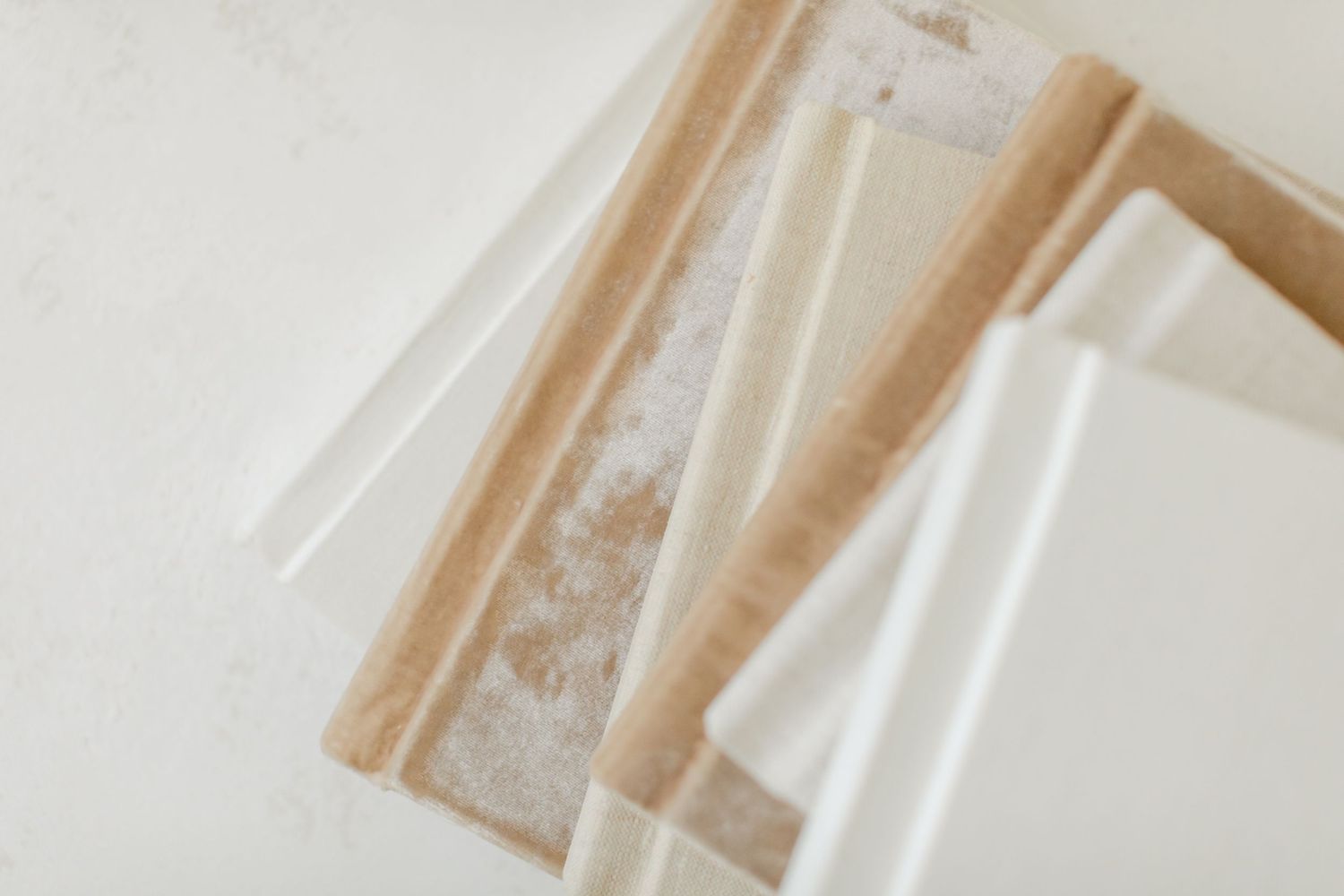 Stacked beige and white linen towels with decorative border detail on a white surface.