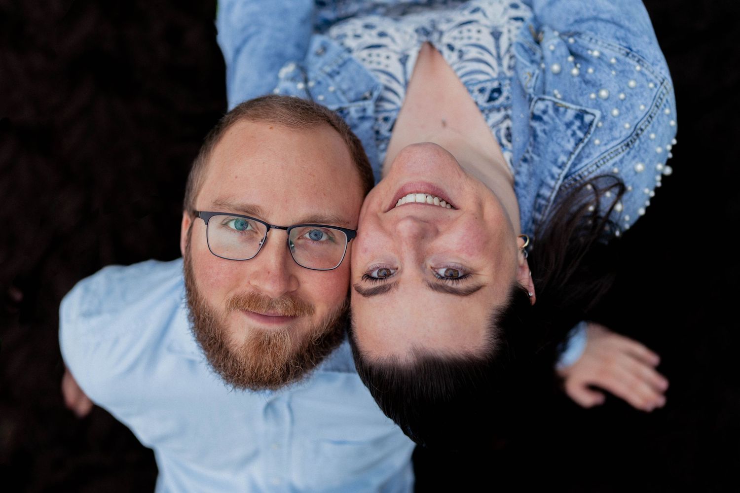 Creative overhead couples portrait with joyful expressions. Playful and intimate engagement photography capturing genuine connection