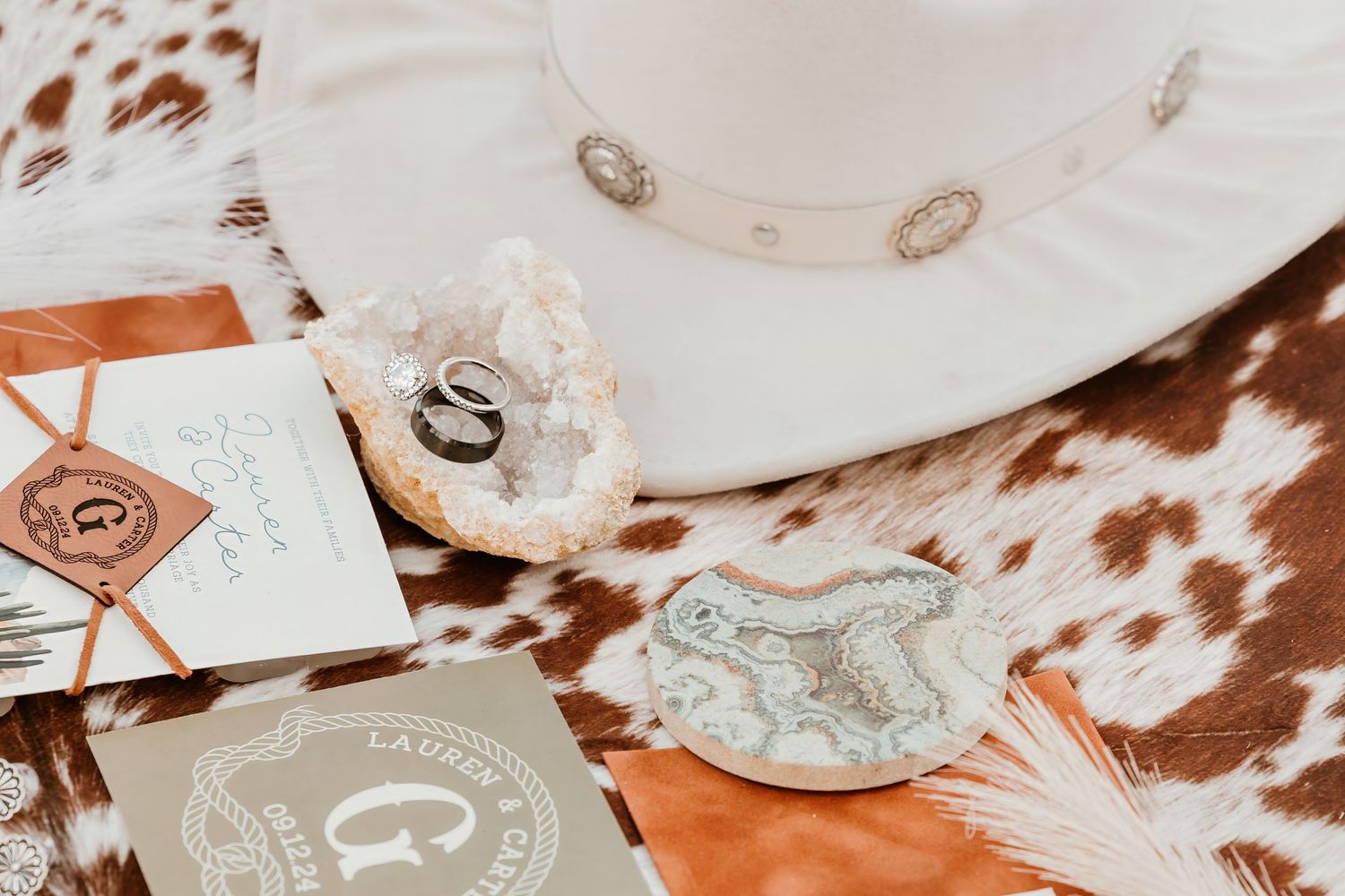 Western-themed flatlay with white cowboy hat and cowhide print accessories.