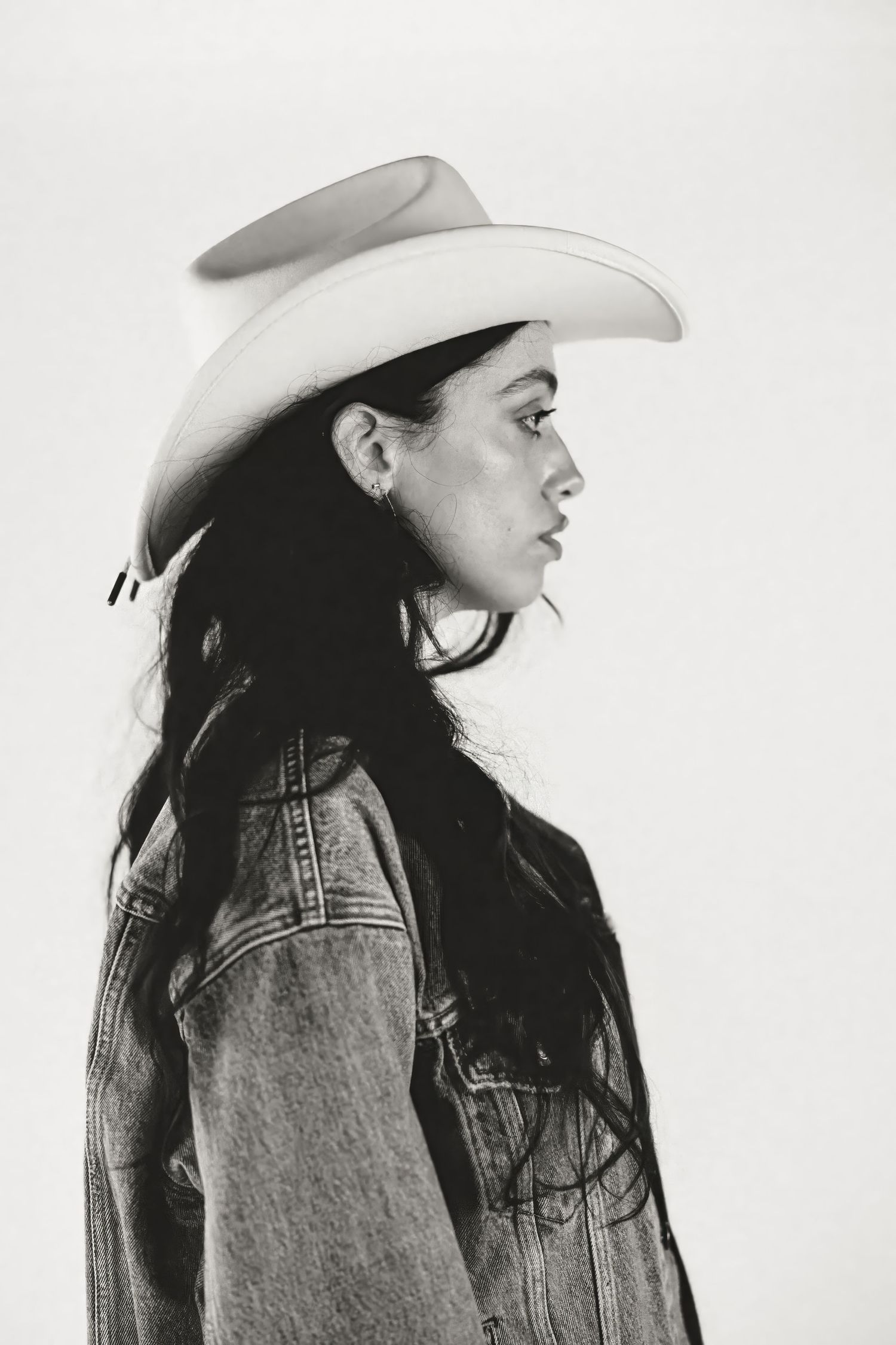 Black and white profile portrait featuring a person in western attire with a light-colored cowboy hat and denim jacket.