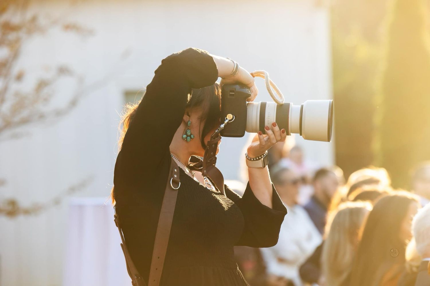 Silhouette of photographer using professional camera with telephoto lens at sunset.