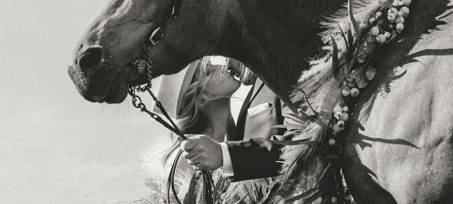 Black and white vintage photo of someone petting a horse's nose.