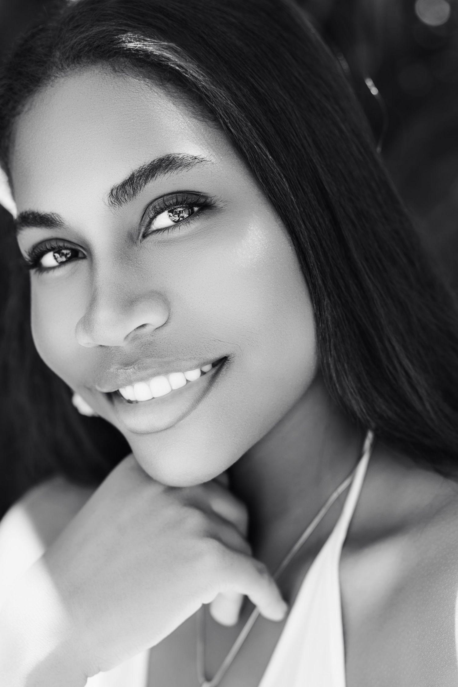 A black and white portrait series showing bright smiles and joyful expressions in natural lighting.