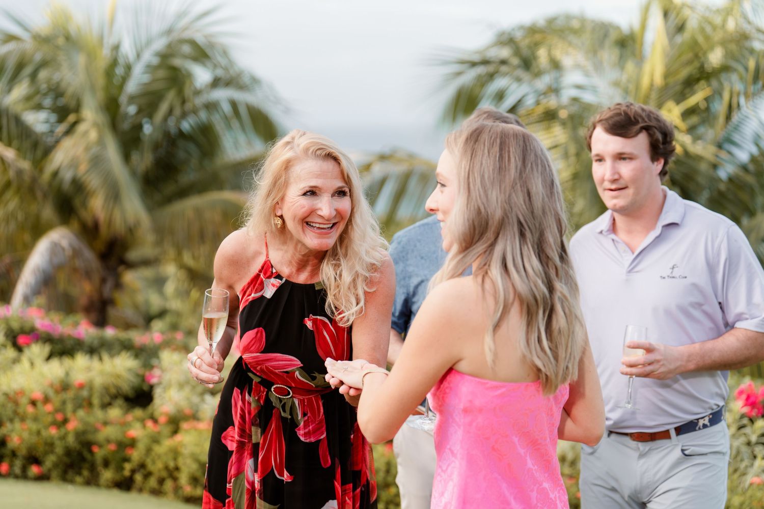Friends socializing and laughing together at an outdoor tropical garden party with palm trees in the background.
