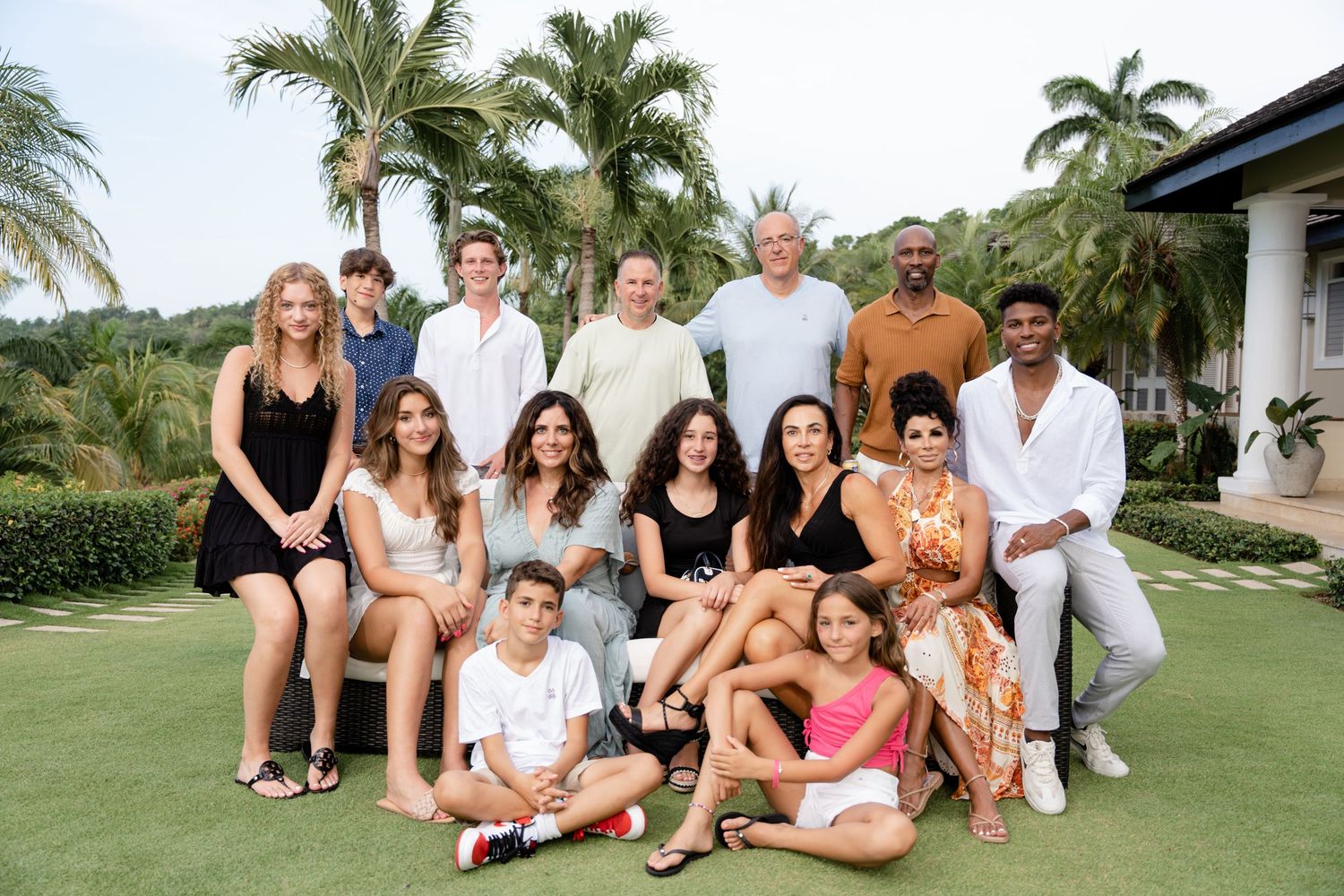 Group relaxes together on a sunny lawn surrounded by tropical palm trees at an upscale resort setting.