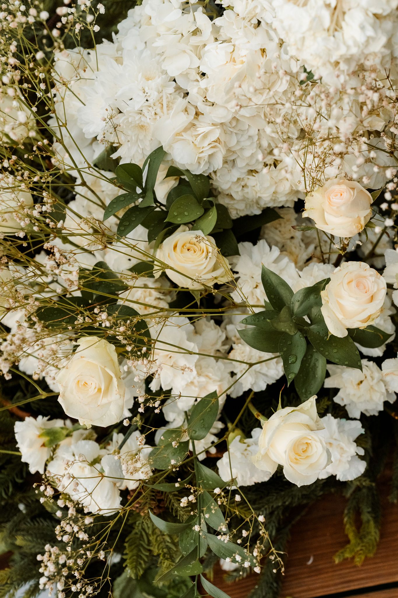 Elegant wedding floral arrangement with white roses, hydrangeas, baby's breath, and green eucalyptus leaves.