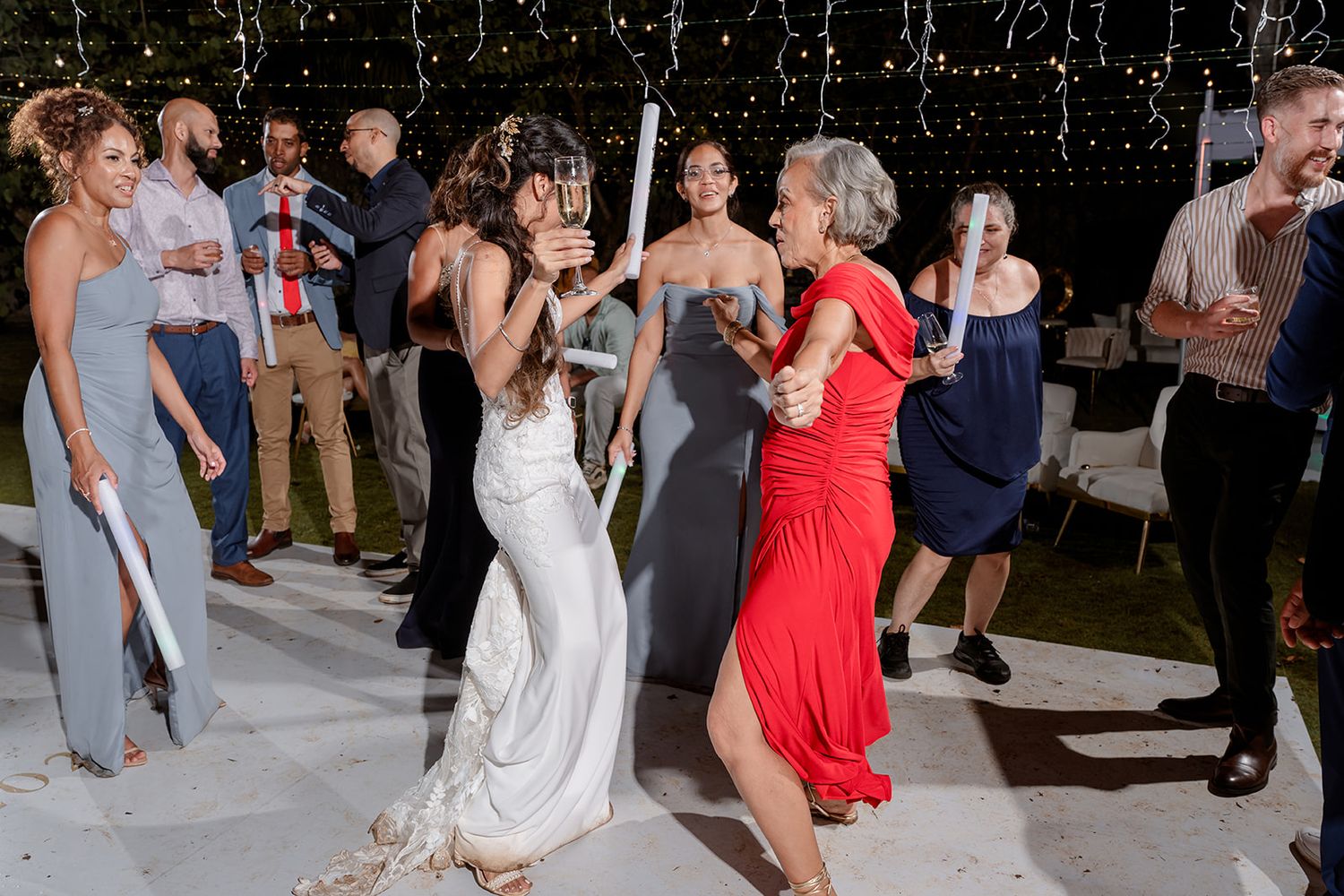 People in formal attire dance and celebrate together at a lively wedding reception on a dance floor.