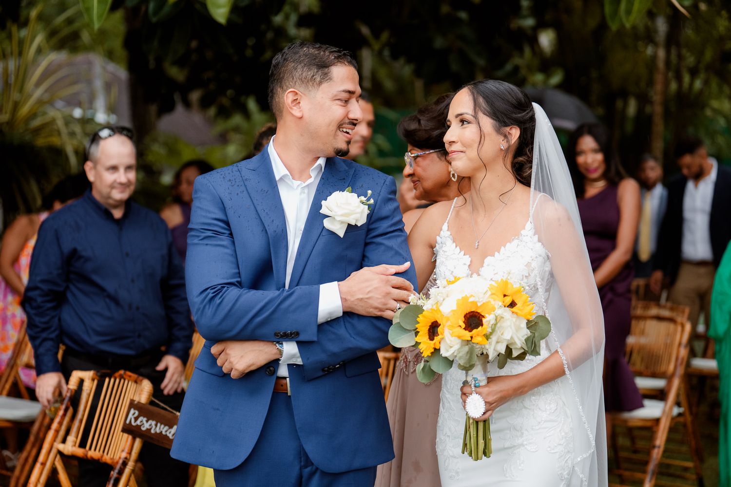 Wedding couple shares joyful moments together during outdoor ceremony with sunflower bouquet.