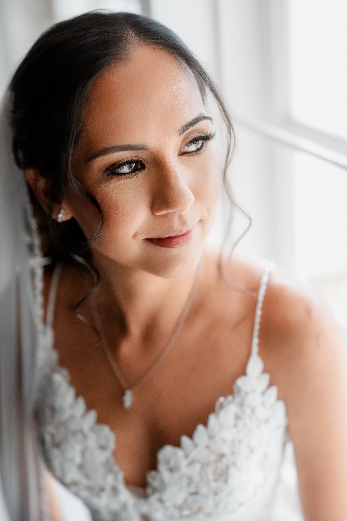 Bride in white lace strap dress with dramatic makeup looks down while smiling in a series of closeup portraits.