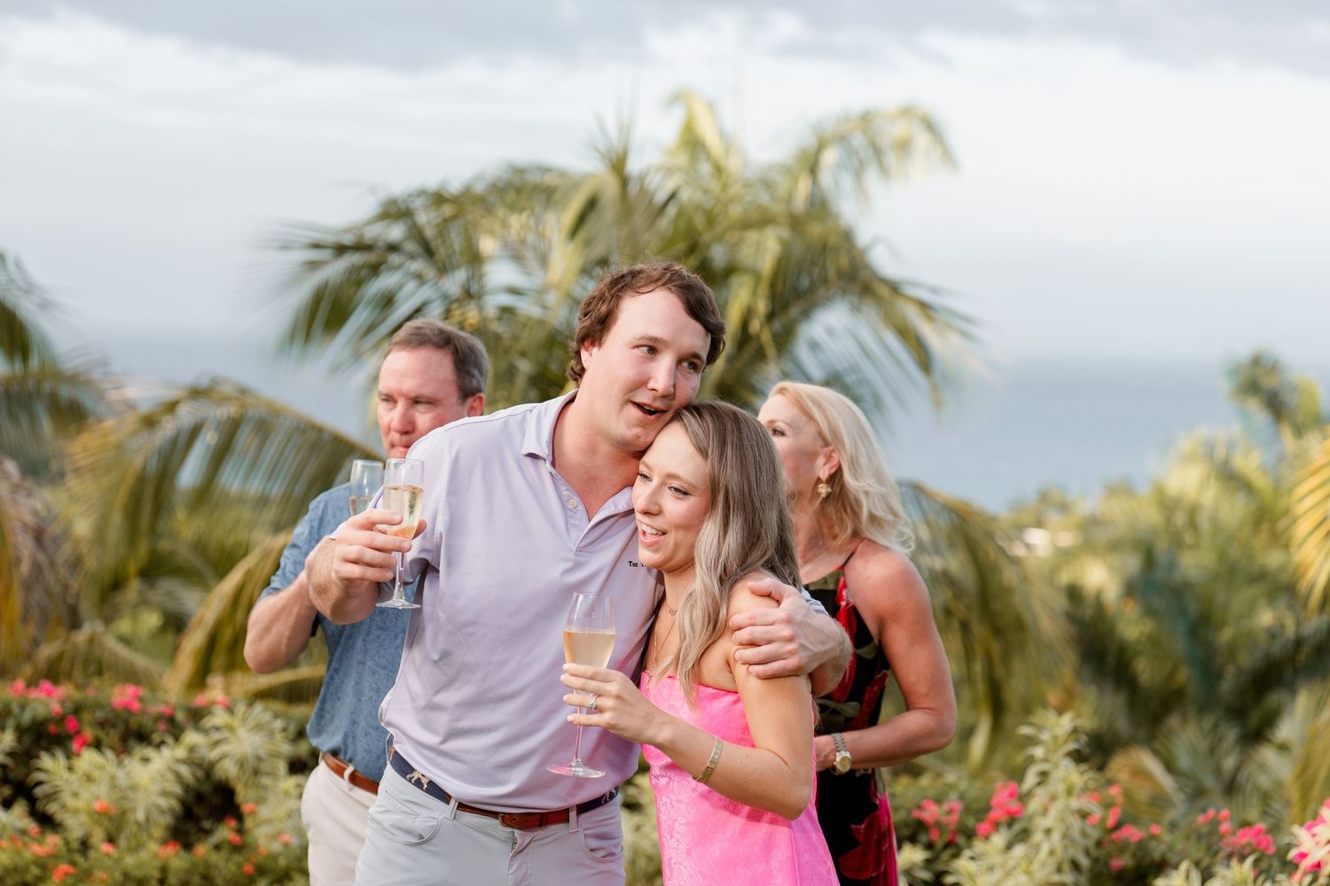 People celebrating outdoors on a tropical patio with palm trees and flowers in the background.