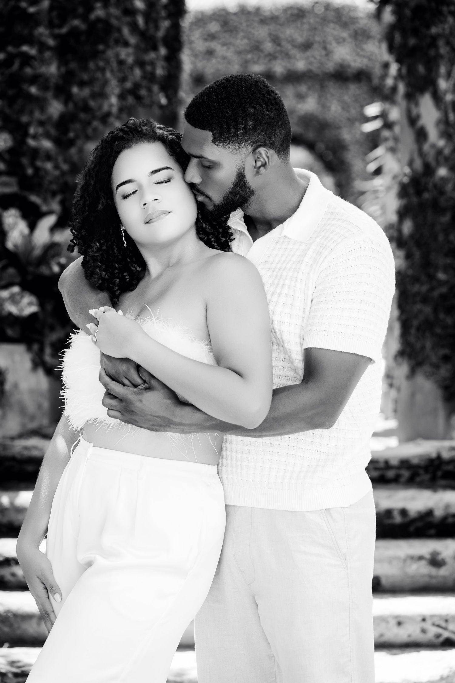 A romantic black and white photo sequence showing a couple in white outfits embracing and sharing tender moments outdoors.