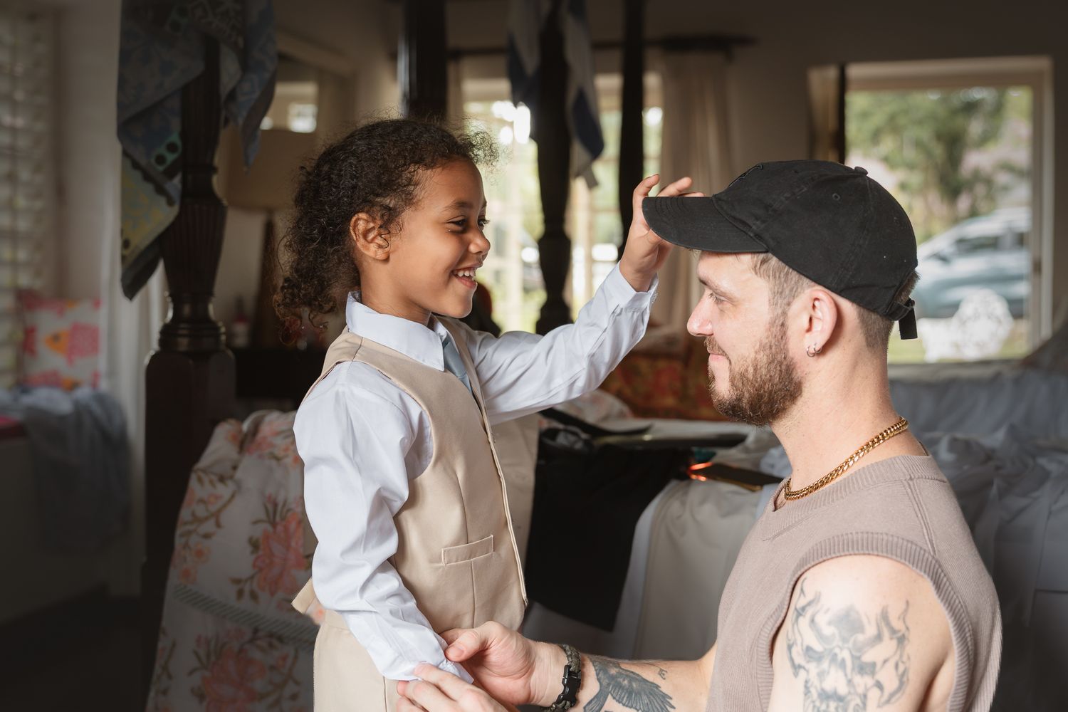 A young girl joyfully touches a bearded man's forehead inside a cozy van, sharing a playful bonding moment.