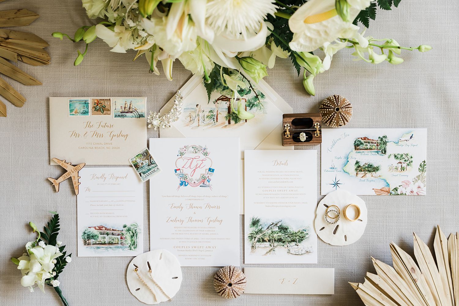 Elegant wedding invitation suite with floral design elements, vintage stamps, and white flowers on a light gray background.