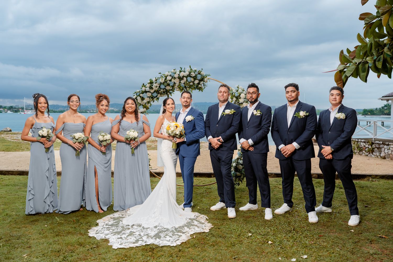 Wedding party poses throughout various beach and waterfront locations in coordinated light colored formal attire.