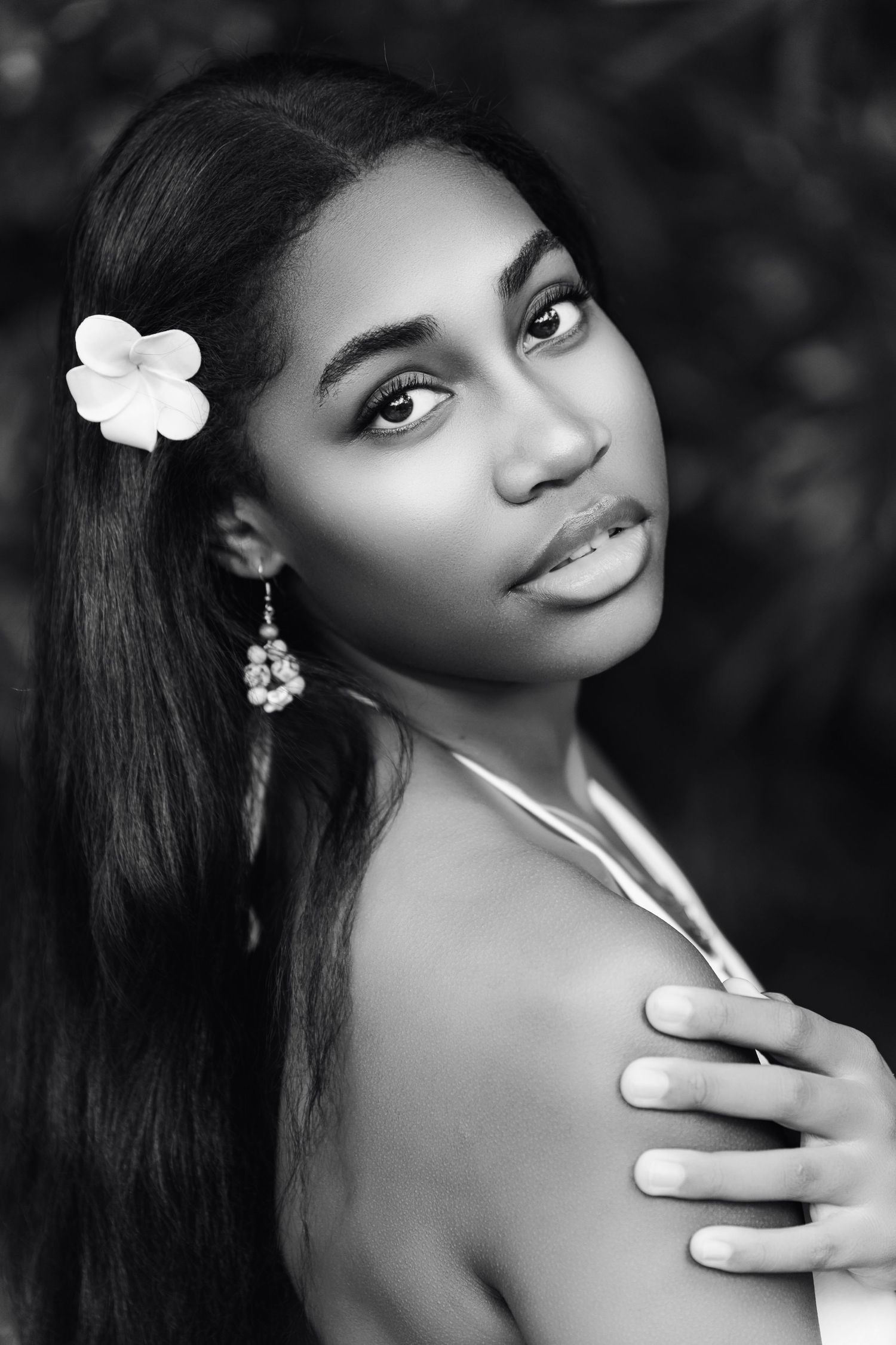 A black and white portrait series shows a person with a white flower in their hair posing gracefully against a dark background.